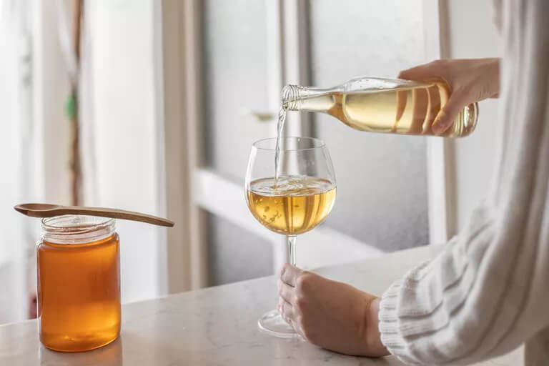 Ett glas vin och en burk honung på bord